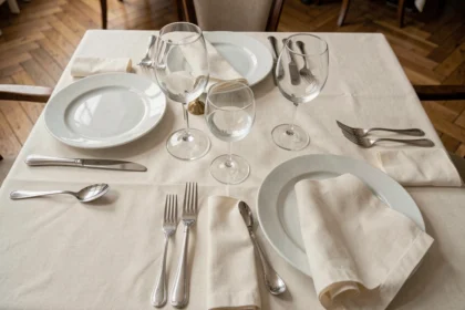 Vue de dessus d'une table de dîner chic à la française avec trois verres en cristal par couvert disposés selon le protocole français